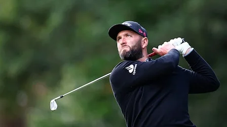 Golfspelare mitt i sitt sving på en solig golfbana